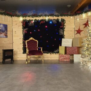 Ensemble de décorations de Noël comprenant : un fond en bois, une boîte aux lettres du Père Noël, un pendrillon lumineux, un trône, trois tapis rouges de cérémonie, six potelets, deux guirlandes stalactites, deux lots de trois sapins lumineux, un feu à bois lumineux, un renne animatronique, deux sets de cadeaux lumineux et un cadre lumineux de Noël. Un décor complet et harmonieux pour créer une ambiance festive et immersive | Le Paradis De Tigrou